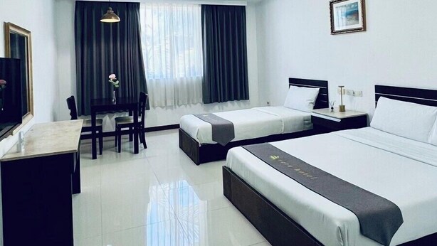 A hotel room with a large bed, a smaller bed, a desk with a chair, a TV, and a window with curtains. - Townhouse Oak Vera Hotel Near Clark International Airport (Angeles City)