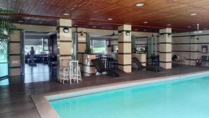 A covered swimming pool area with a wooden ceiling, seating, and a bar area. - Townhouse Oak Vera Hotel Near Clark International Airport (Angeles City)