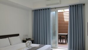 A hotel room with a bed, a nightstand, a swan decoration, and a sliding glass door leading to an outdoor area. - Townhouse Oak Vera Hotel Near Clark International Airport (Angeles City)