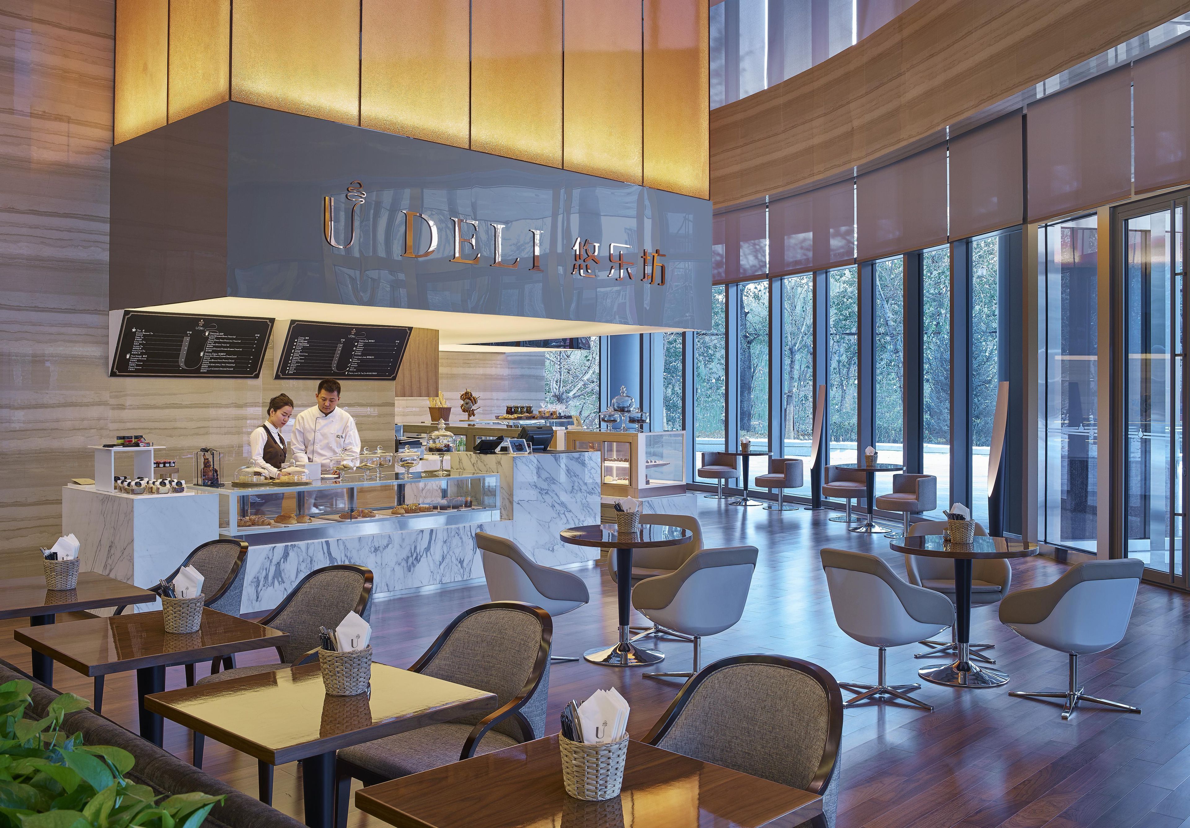 A modern cafe interior with marble counters, seating areas, and large windows.