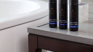 A bathroom with a white sink, a mirror, and three black bottles of NUO organic hair wash and shampoo on a dark wooden table.