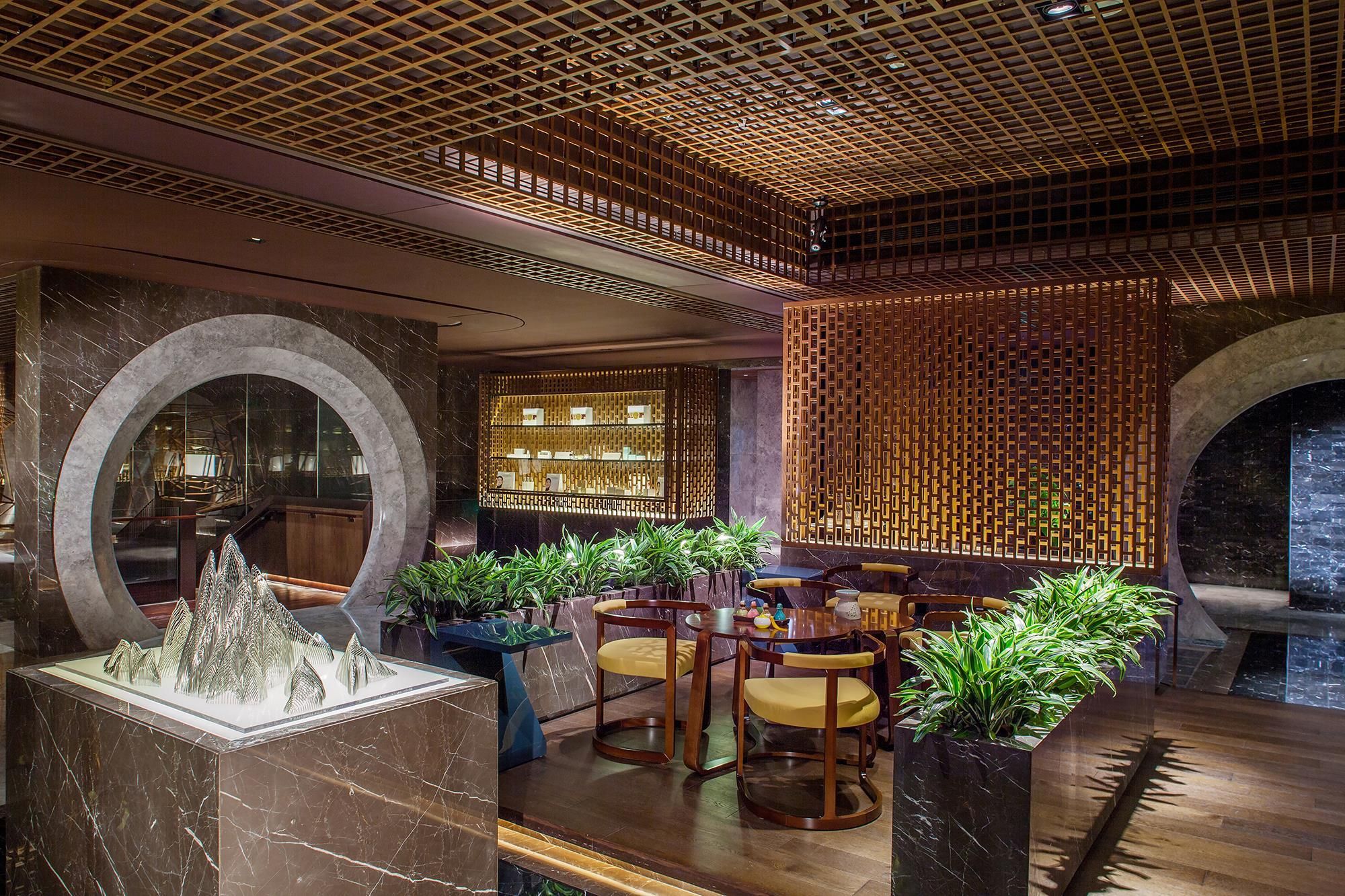 A modern interior with a wooden ceiling, marble flooring, and a seating area with chairs and tables.