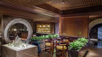 A modern interior with a wooden ceiling, marble flooring, and a seating area with chairs and tables.