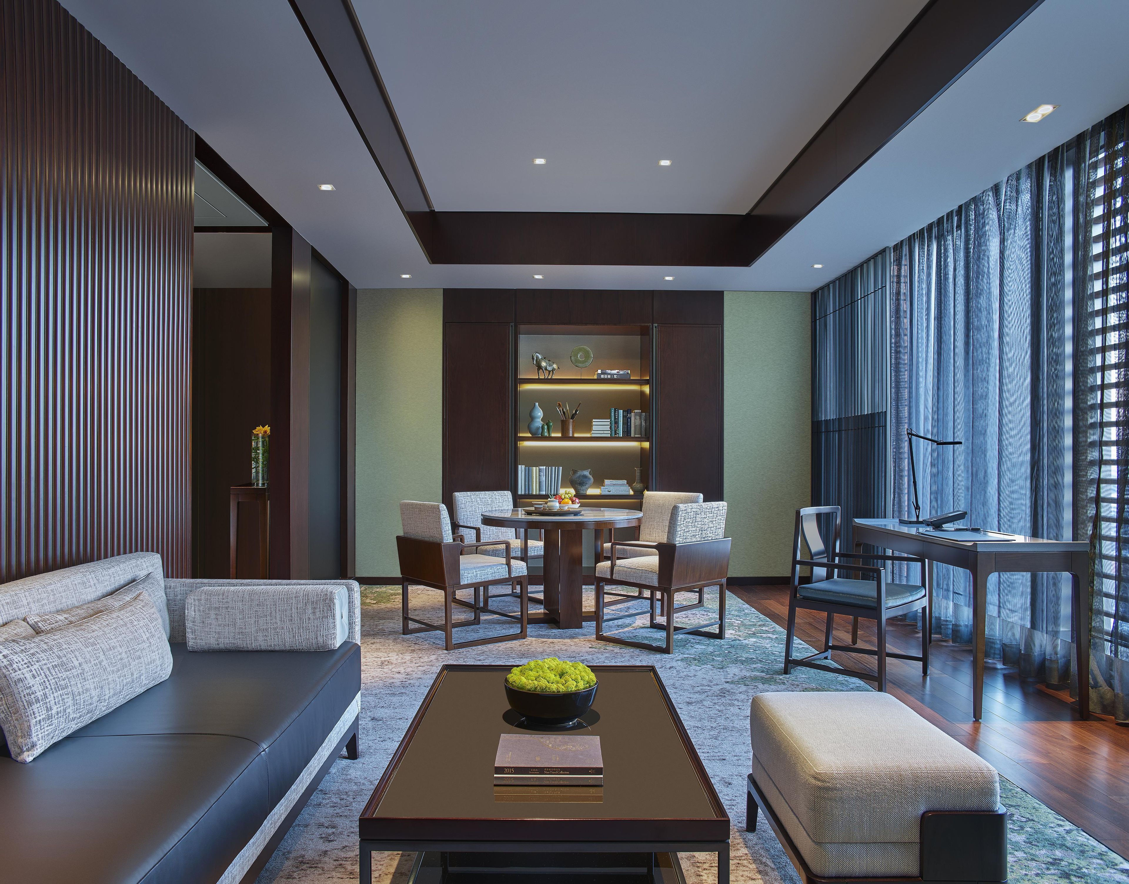A modern living room with a sofa, chairs, a coffee table, and a bookshelf.