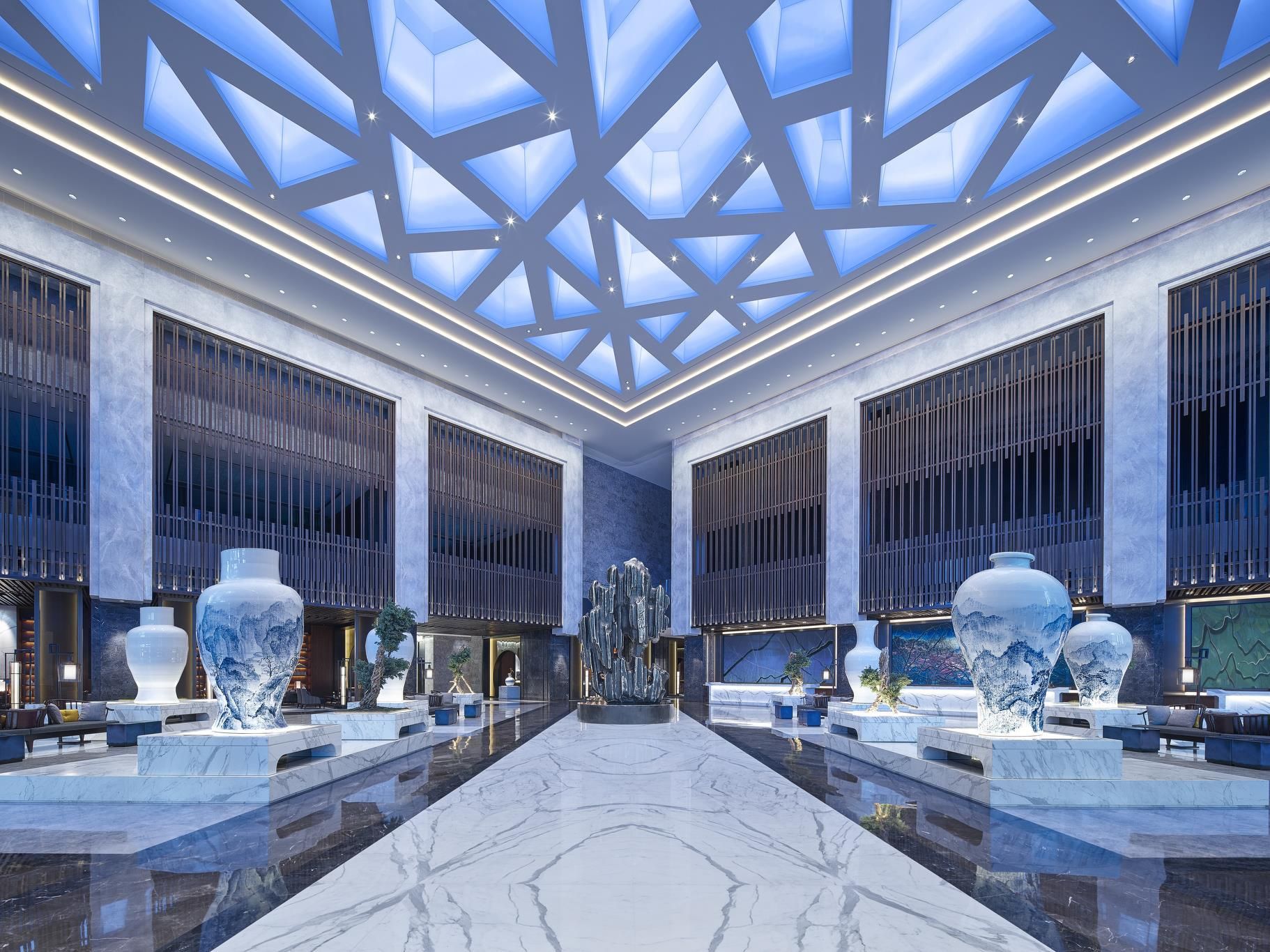 A spacious lobby with a high ceiling, large windows, and a central marble floor.