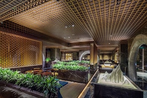 A lobby with a patterned ceiling, seating areas, and a water feature.