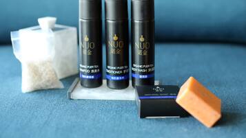 Three black bottles labeled "NUO" on a blue surface with a white container and a small orange object.