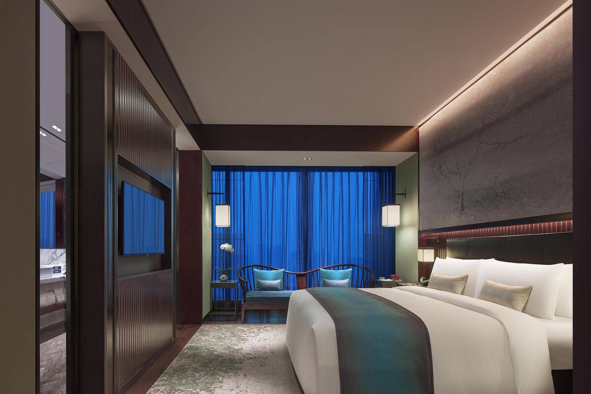 A modern hotel room with a large bed, a desk, and a television.