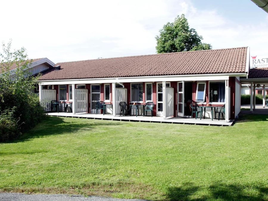A two-story building with a red-tiled roof, a covered outdoor seating area with tables and chairs, and a sign for 'Rasta Country Kitchen'.