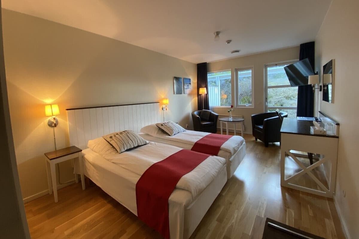 Una habitación de hotel con dos camas, un escritorio, una silla y una mesita.