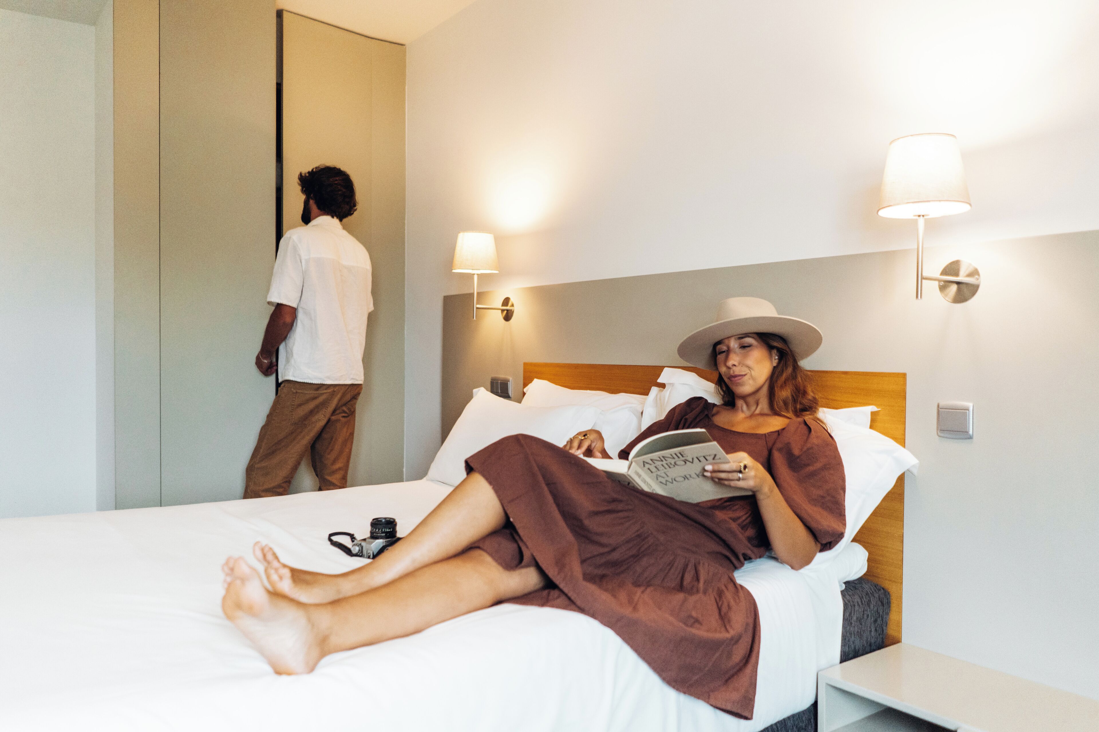 Una habitación de hotel con una cama, una mesita de noche y un espejo.