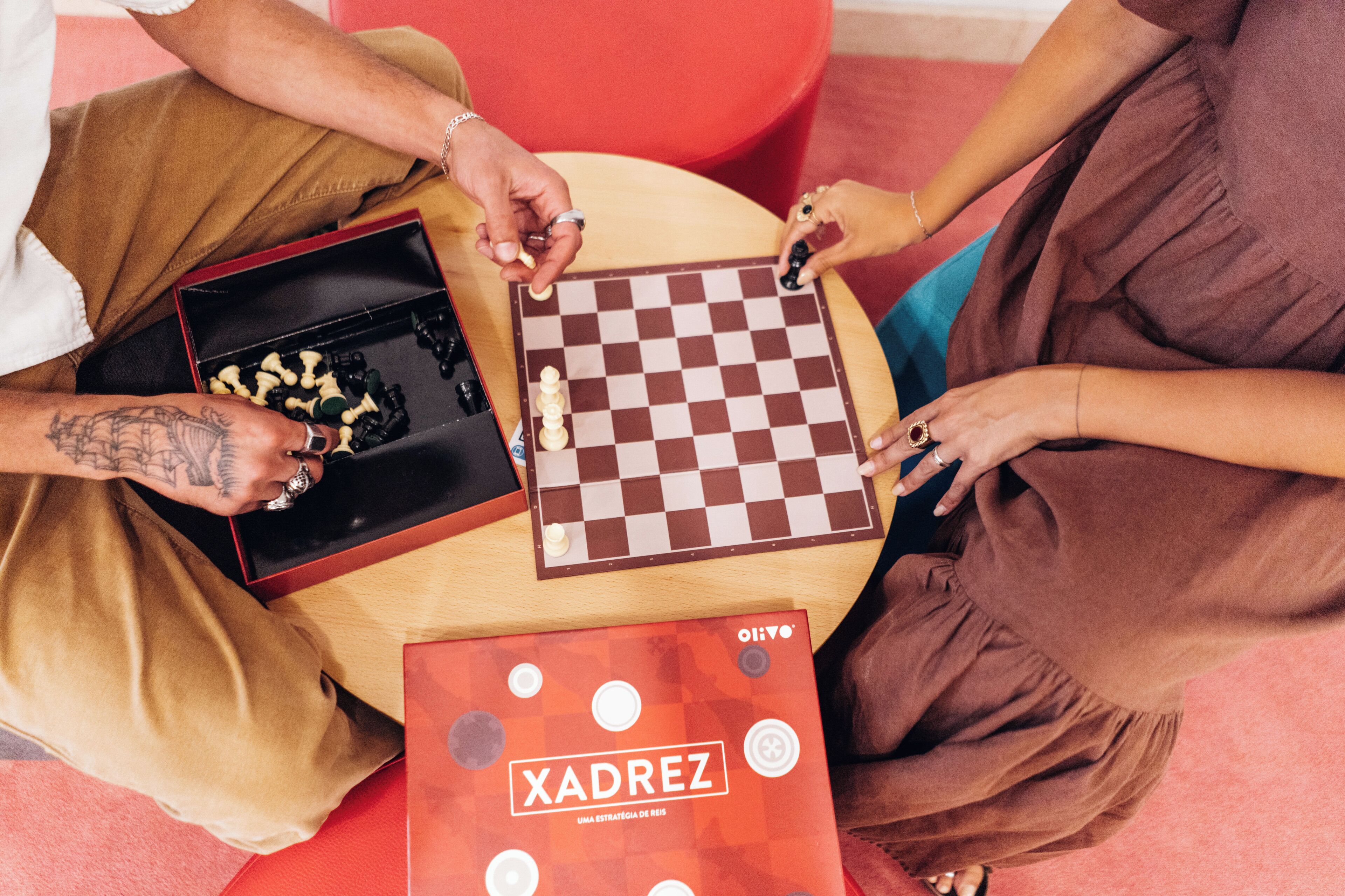 A group of people playing chess at a table with a book titled "XADREZ" on it.