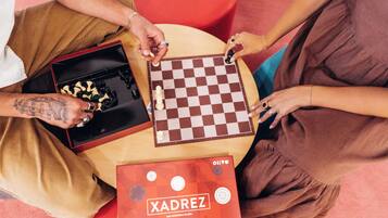 A group of people playing chess at a table with a book titled "XADREZ" on it.