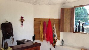 A room with a wooden desk, a small statue, and a window with decorative items. - Pousada Marajoara (Soure)