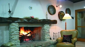 Una chimenea de piedra con fuego, un sillón de cuero y decoración en la pared.