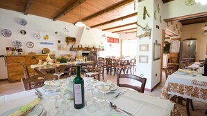 Comedor con mesas dispuestas para una comida, una botella de vino y diferentes platos.