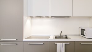 Une cuisine moderne dotée d’un évier en acier inoxydable, d’un four à micro-ondes et d’une serviette suspendue à un porte-serviettes.