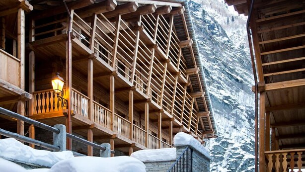 Un chalet en bois doté d’un balcon et d’un mur en pierre.
