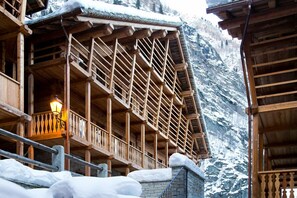 Un chalet en bois doté d’un balcon et d’un mur en pierre.