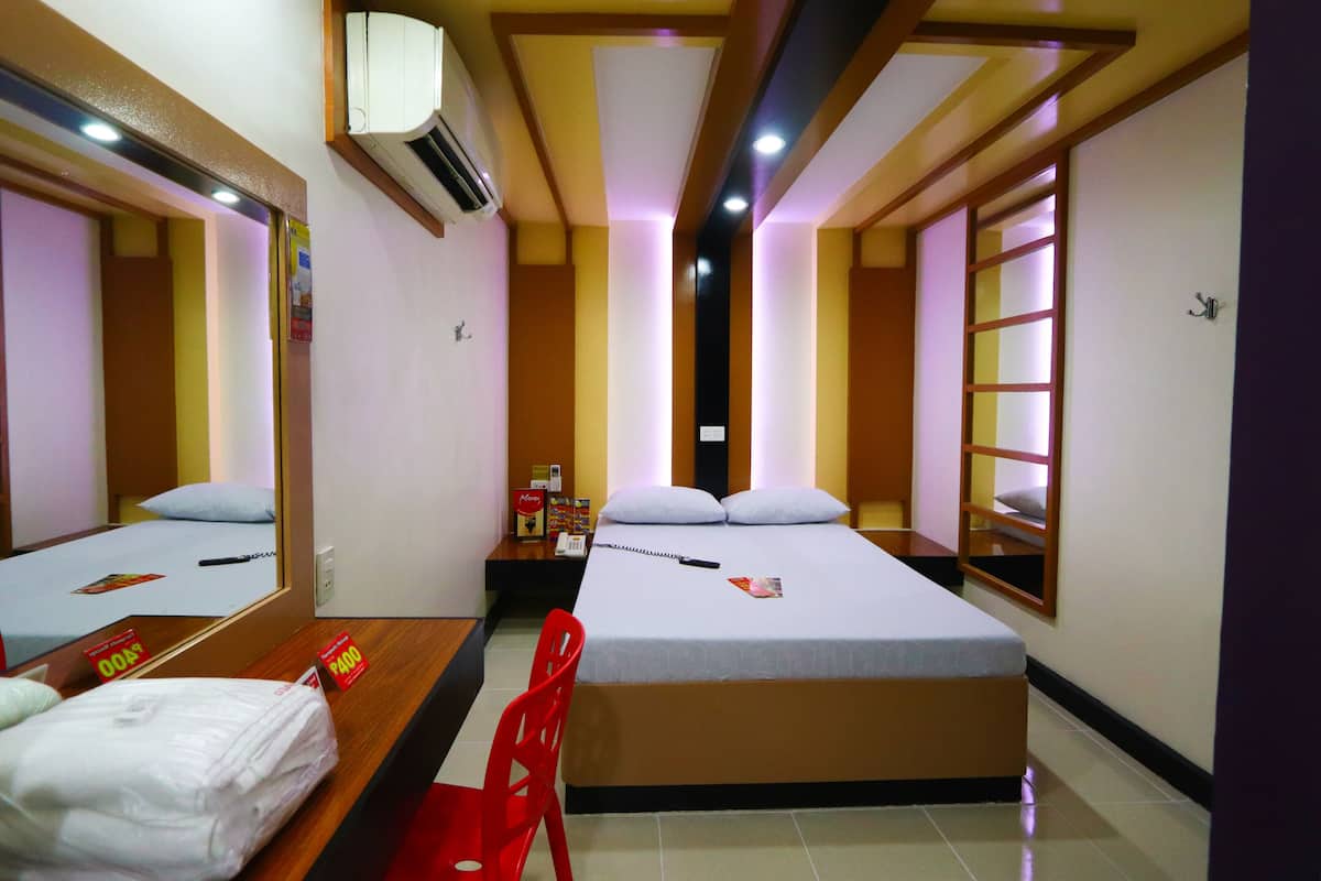 A hotel room with two beds, a desk, a chair, and a mirror.