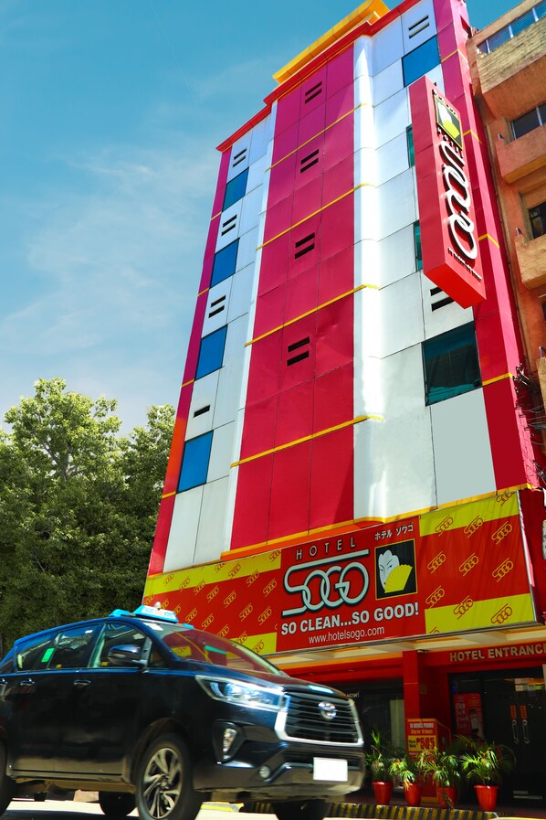 A multi-story hotel building with a prominent red and white facade, featuring a large sign with the hotel's name and a slogan. - Hotel Sogo Cebu (Cebu City)