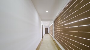 A narrow hallway with white walls and a wooden panel wall on one side.