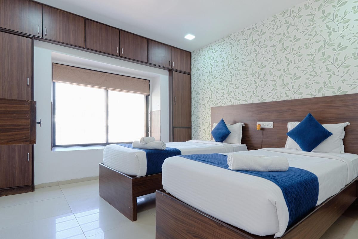 A hotel room with two beds, wooden headboards, and a large window.