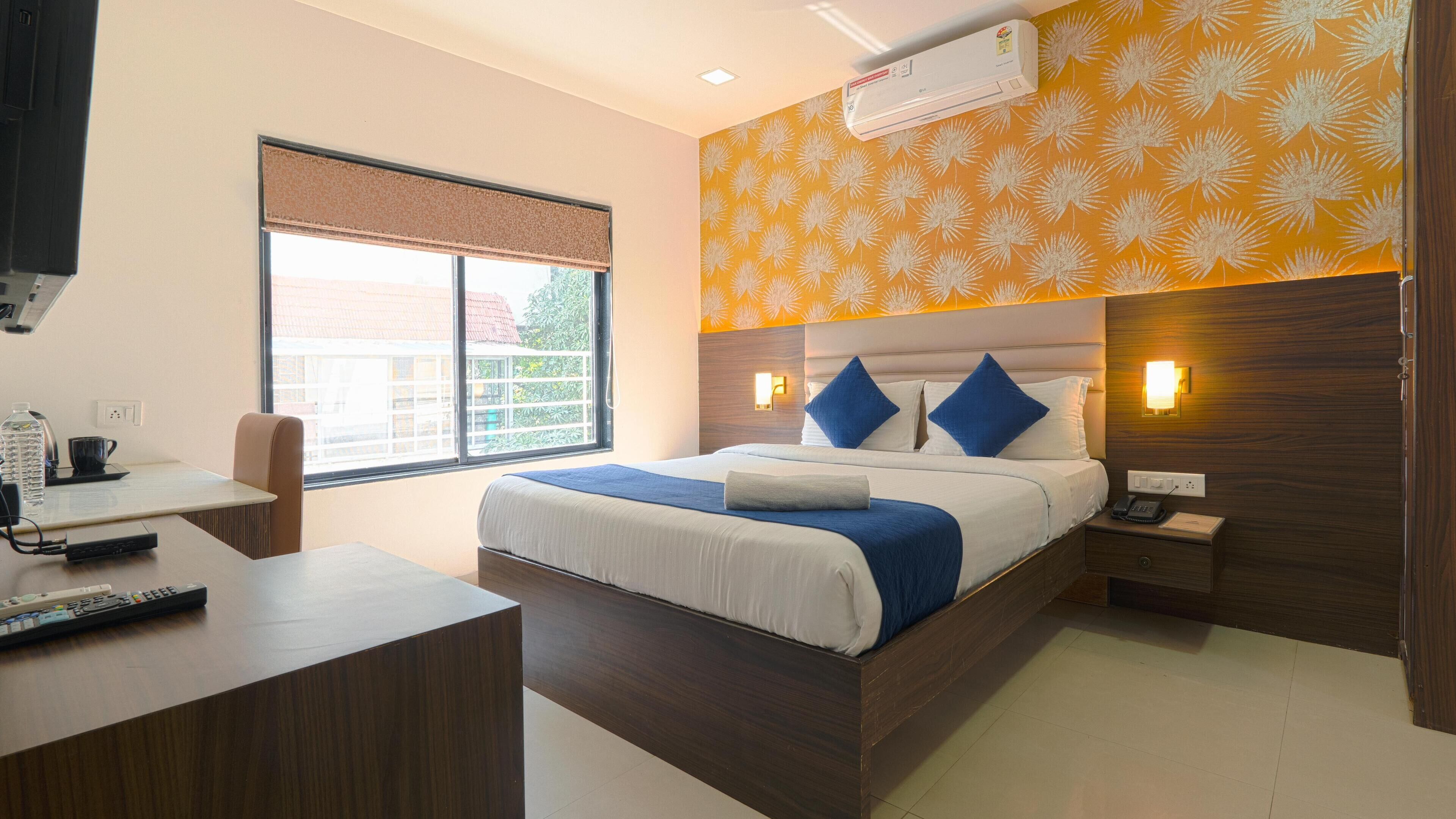 Una habitación de hotel con cama, mesita de noche y escritorio con silla.