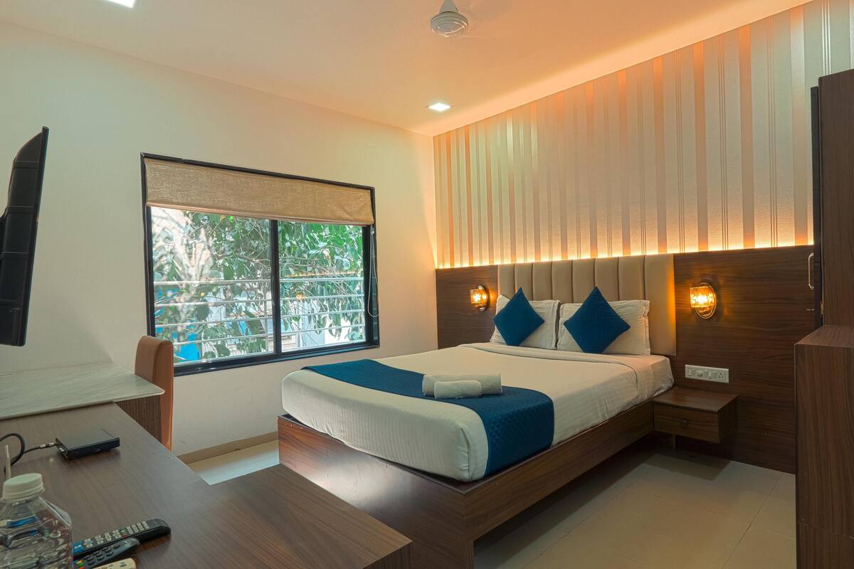 A modern hotel room with a large bed, a desk, and a TV.