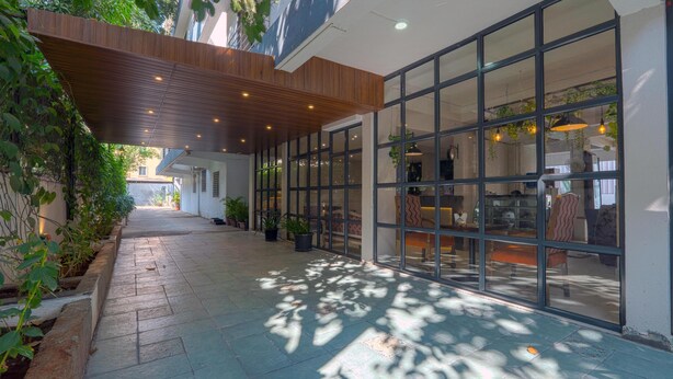 A covered outdoor area with a wooden ceiling, large glass windows, and potted plants.