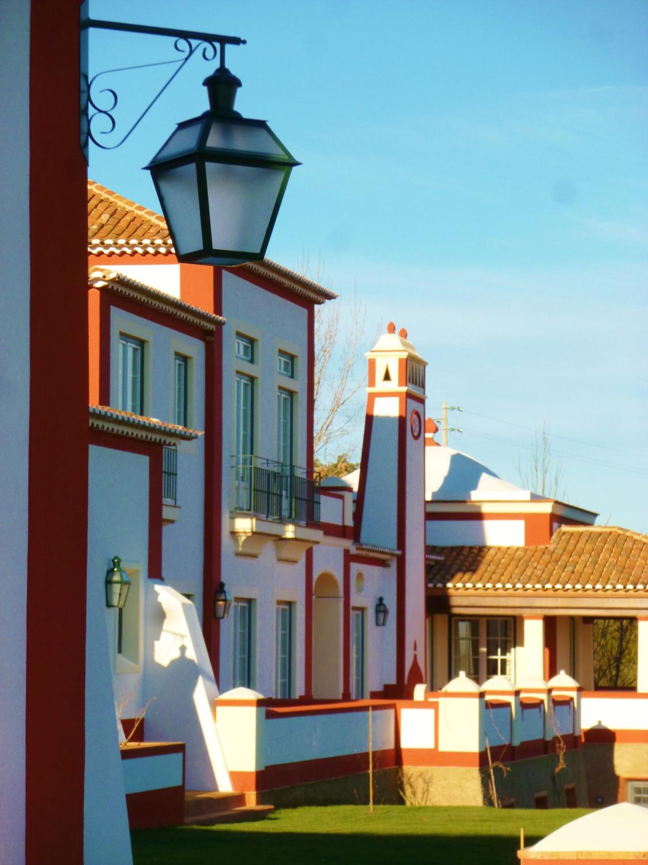 Un edificio con fachada roja y blanca, una torre de campanas y un balcón.