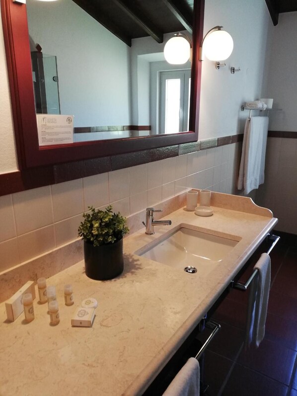 A bathroom with a large mirror, two sinks, a potted plant, and a towel rack. - Hotel Rural Monte da Provença (Elvas)