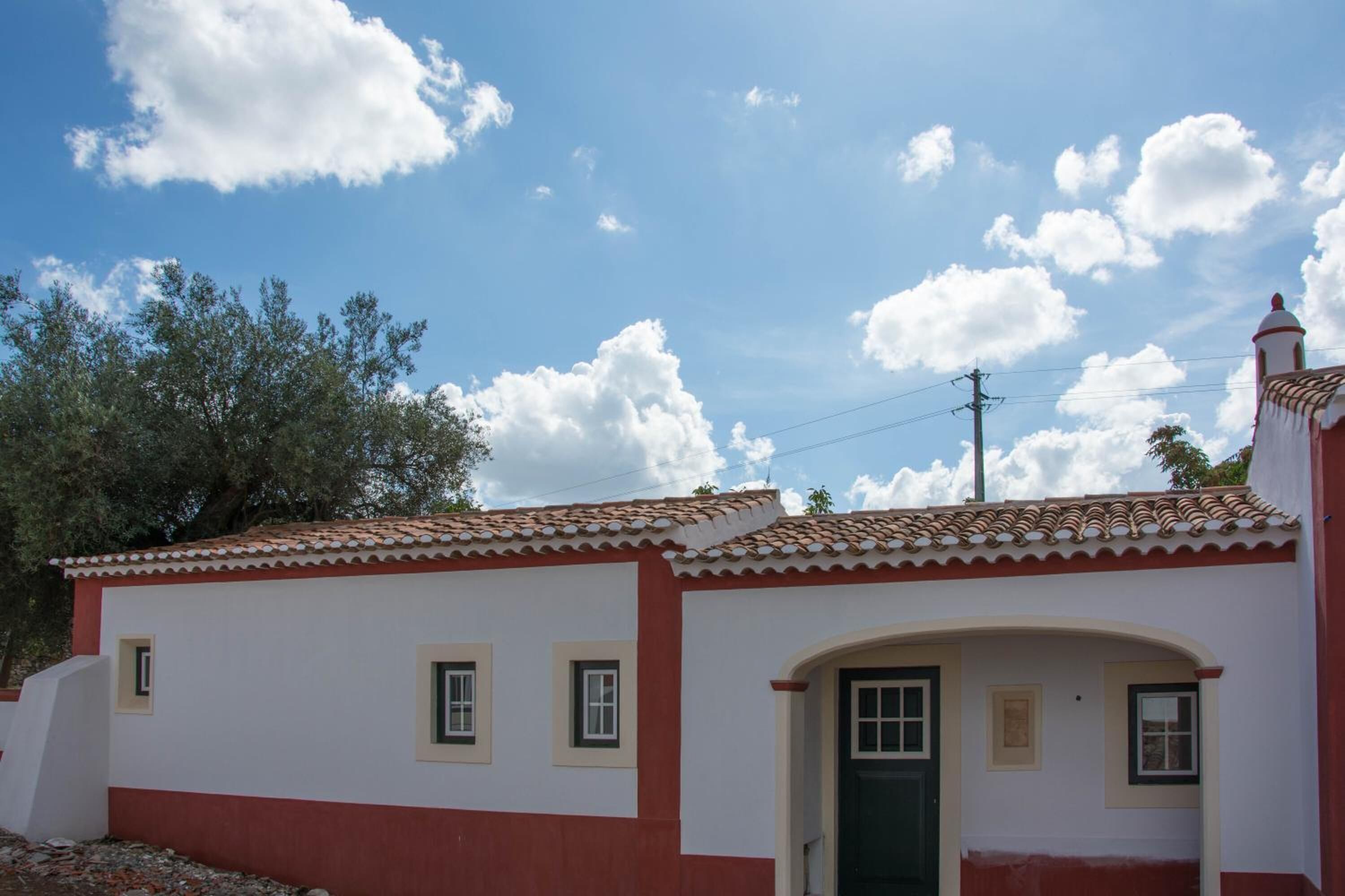 A small, single-story building with a tiled roof and a green door.