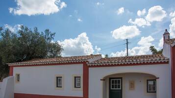 A small, single-story building with a tiled roof and a green door.