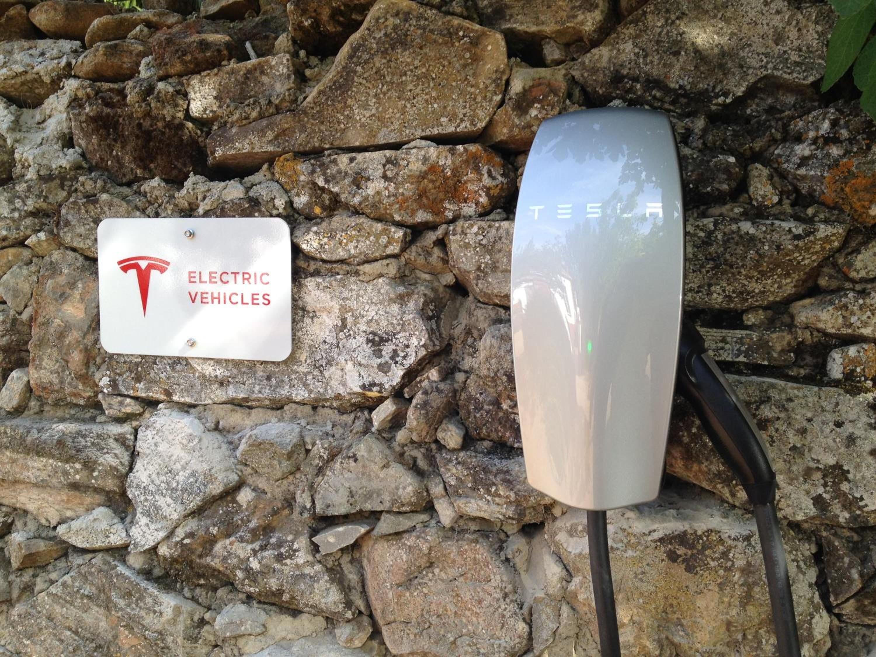A Tesla electric vehicle charging station with a sign indicating it is for electric vehicles.