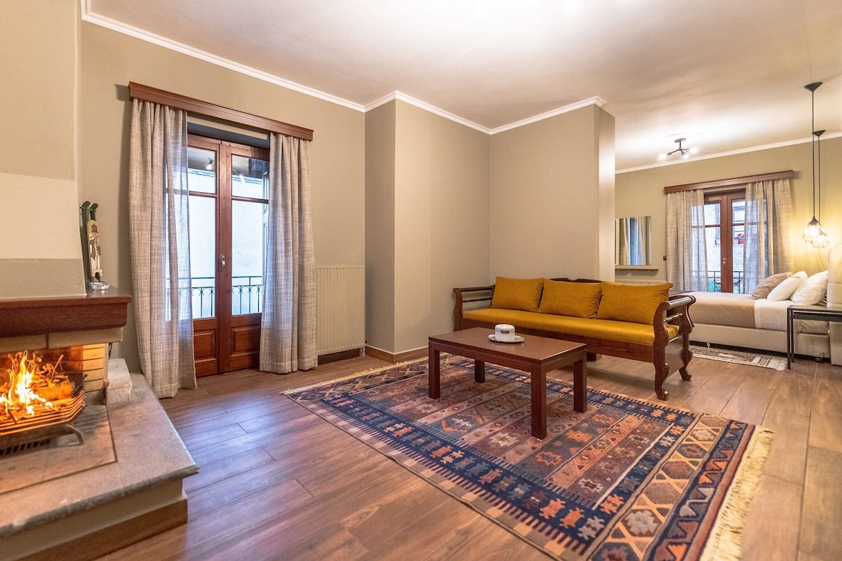 Ein Wohnzimmer mit Kamin, einer Couch, einem Couchtisch und einem gemusterten Teppich.