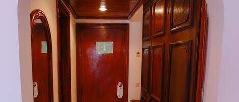 A hallway with a marble floor, wooden doors, and an arched ceiling.