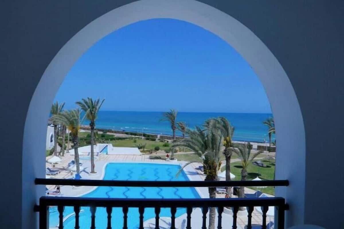 Ein Balkon mit Blick auf ein Schwimmbecken und den Ozean.