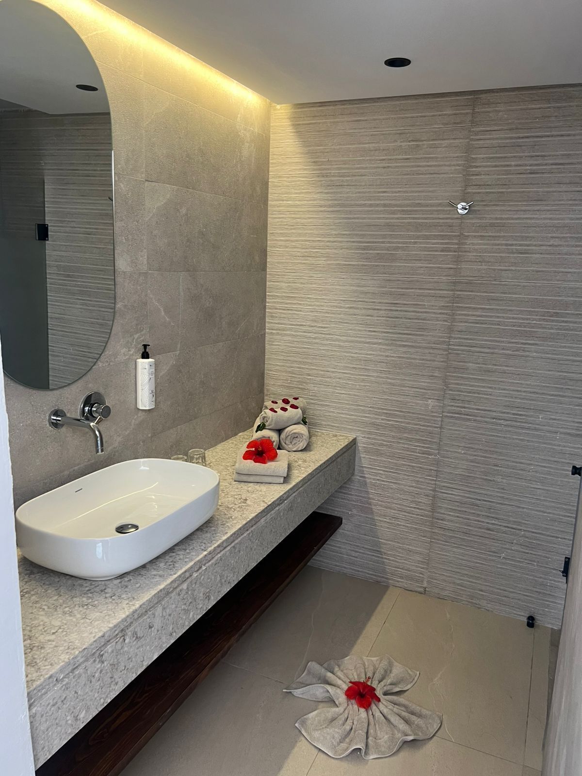 A modern bathroom with a large oval sink, a mirror, and a towel rack.