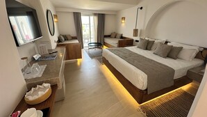 A modern hotel room with a large bed, a desk, and a seating area with a view of the outdoors. - Aljazira Beach & Spa  -  Families and Couples Only (Mezraia)