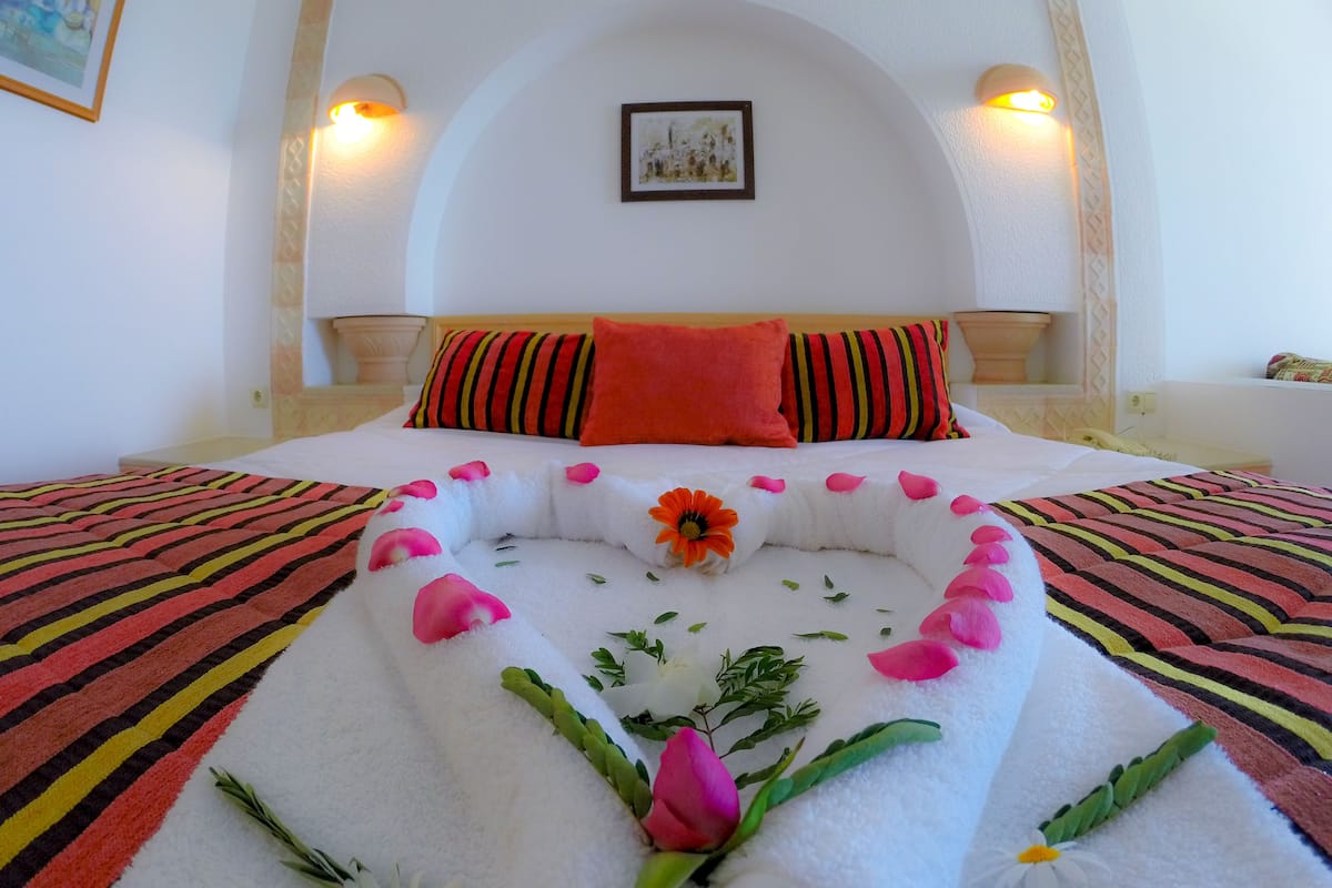 Ein ordentlich bezogenes Bett mit Blumenarrangements und gestreifter Bettwäsche.