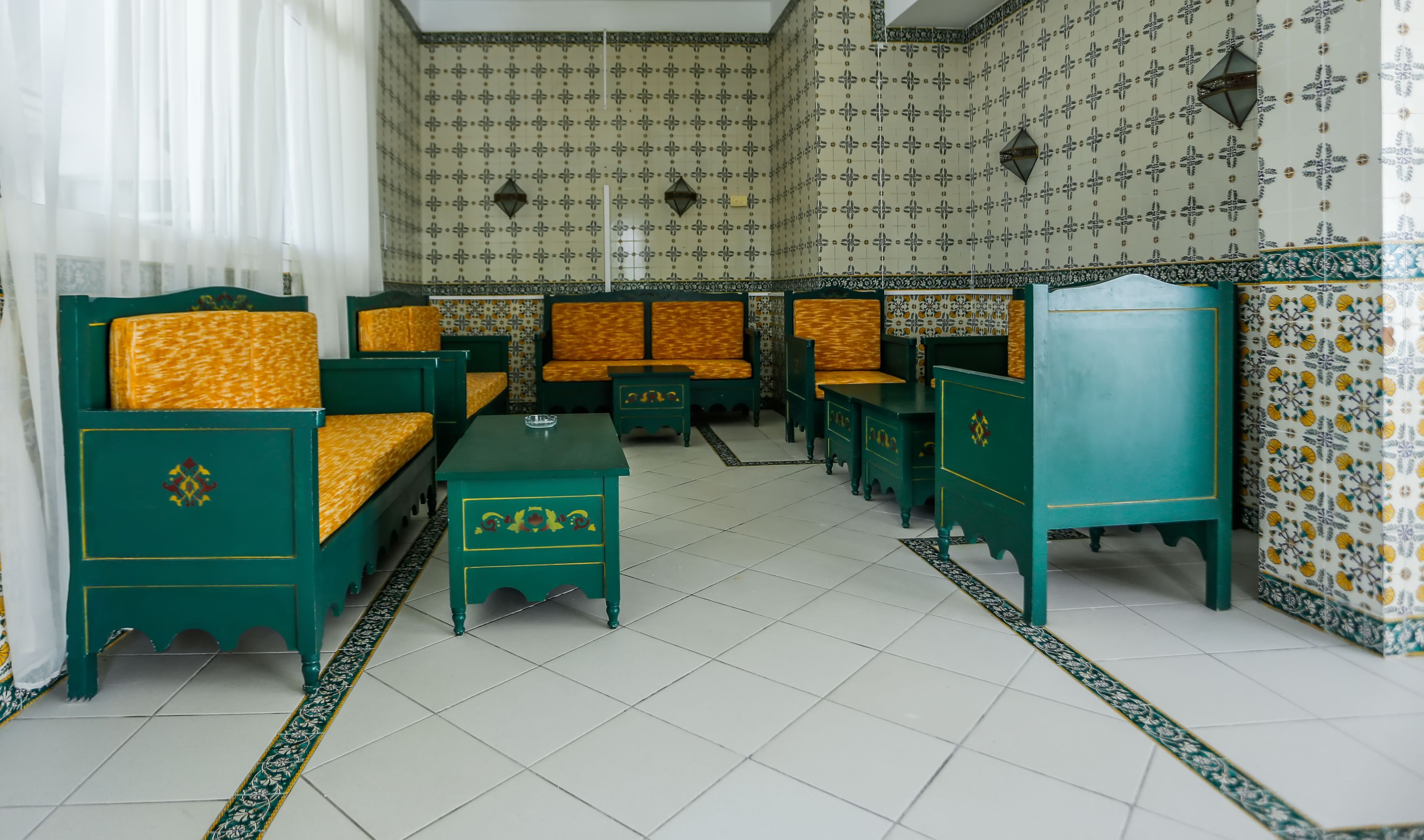 A traditional room with green furniture, patterned wallpaper, and a tiled floor.