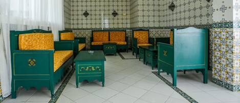 A traditional room with green furniture, patterned wallpaper, and a tiled floor.