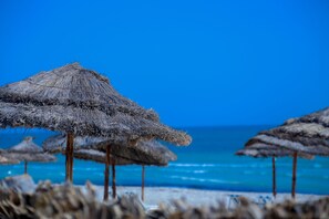 A beach with thatched umbrellas and a clear blue sky. - Aljazira Beach & Spa  -  Families and Couples Only (Mezraia)
