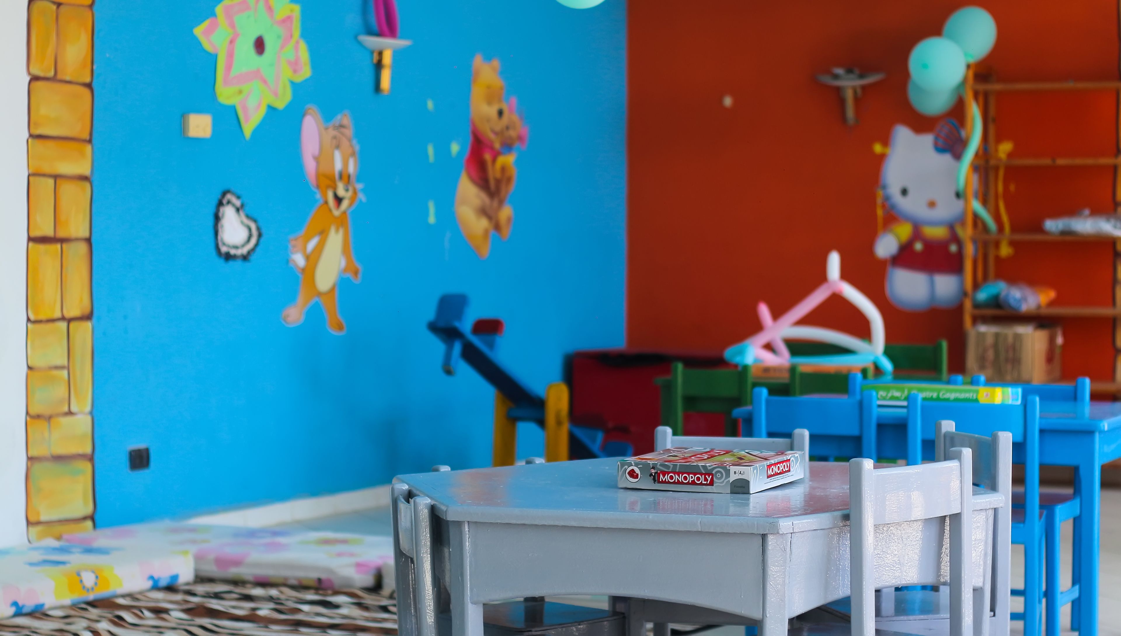 A children's playroom with colorful decorations, a Monopoly board game, and a Hello Kitty balloon.