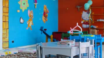 Une salle de jeux pour enfants, décorée de couleurs vives, avec un jeu de société Monopoly et un ballon à l’effigie de Hello Kitty.