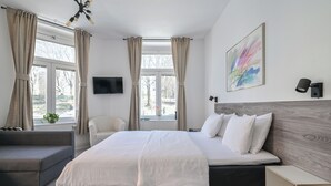 A modern hotel room with a large bed, a sofa, a TV, and a painting on the wall. - Hotel Bema (Stockholm)