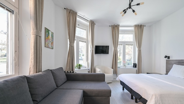 A modern bedroom with a grey sofa, a bed, and a chair. - Hotel Bema (Stockholm)