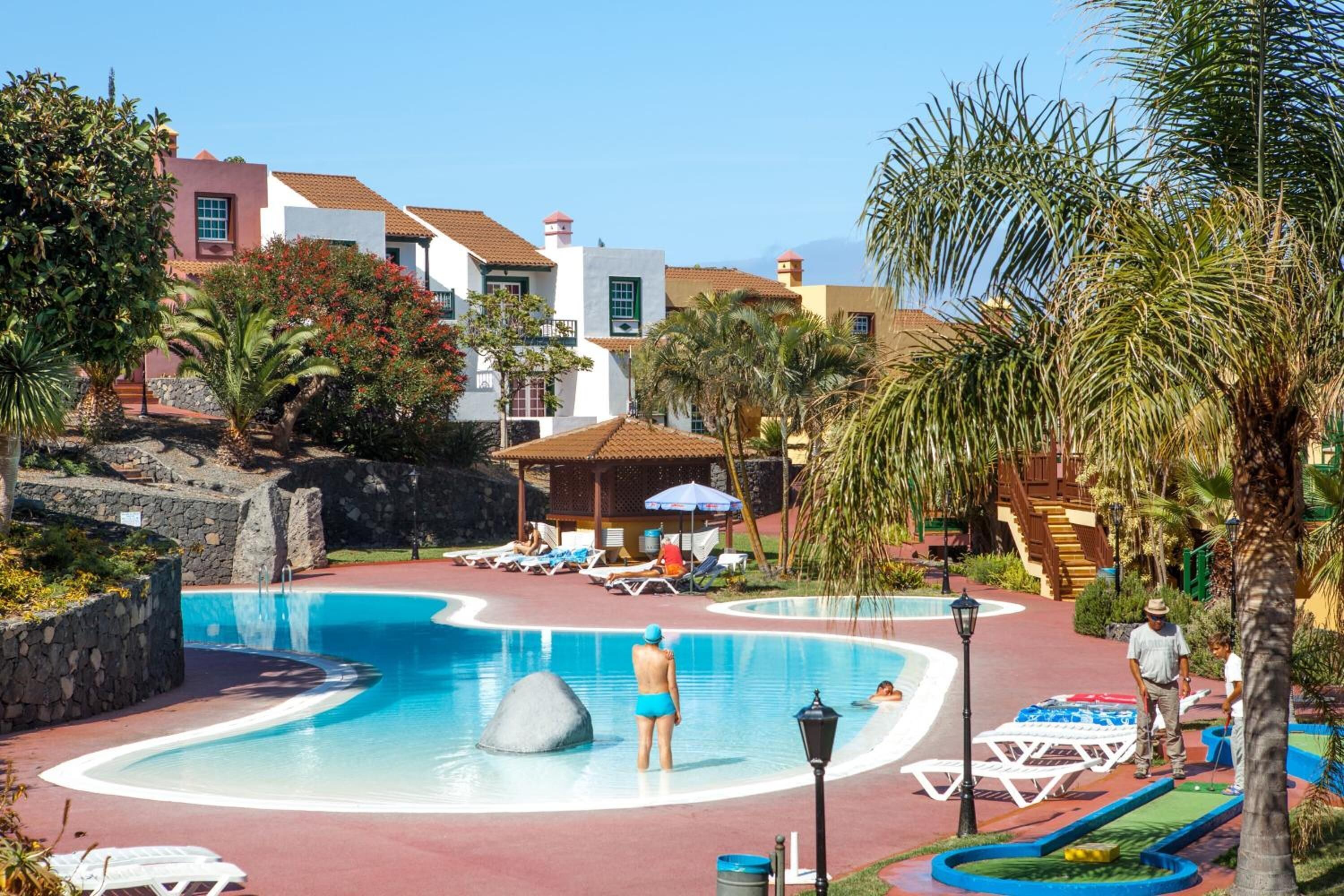 Una piscina con sillas de descanso y un pabellón.