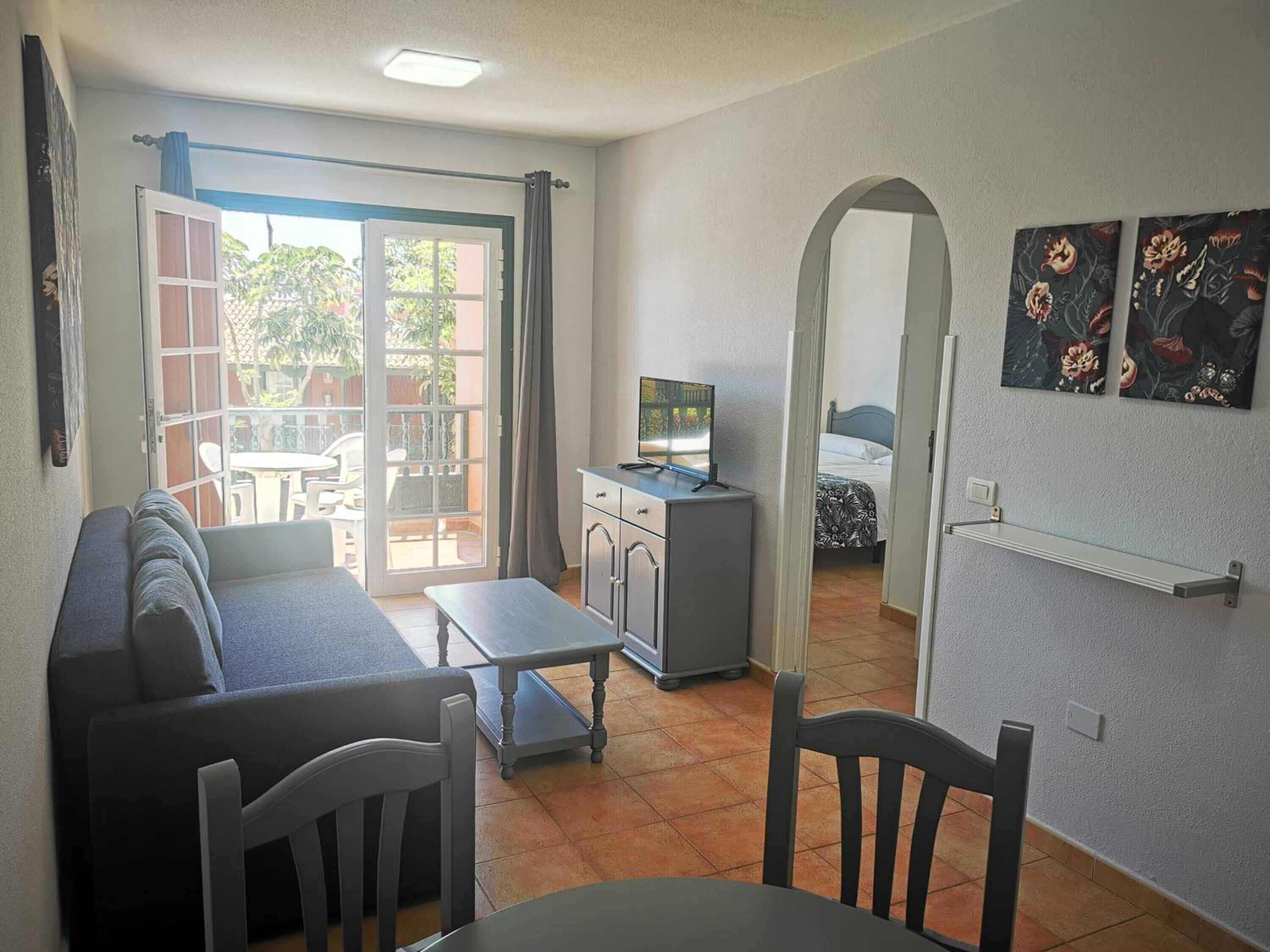 Un espace de vie compact comprenant un canapé, une table à manger et une petite kitchenette.